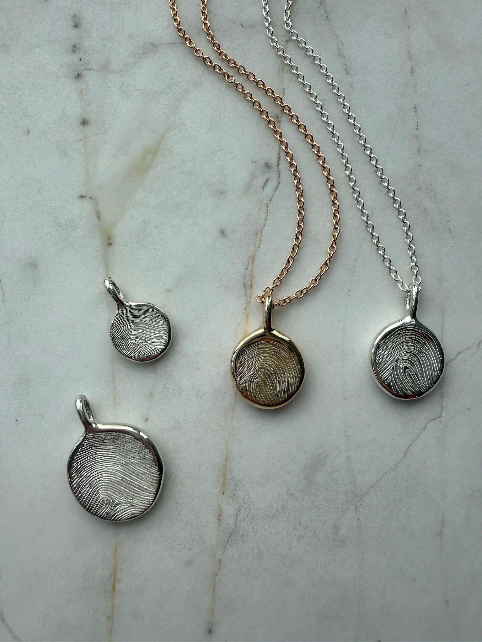 Three necklaces with round pendants on a marble surface