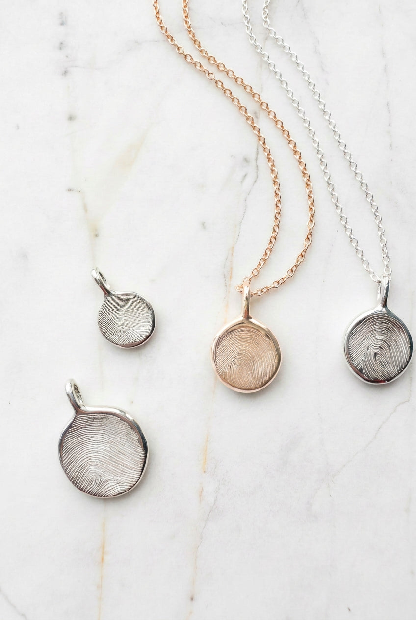 Three necklaces with round pendants on a marble surface
