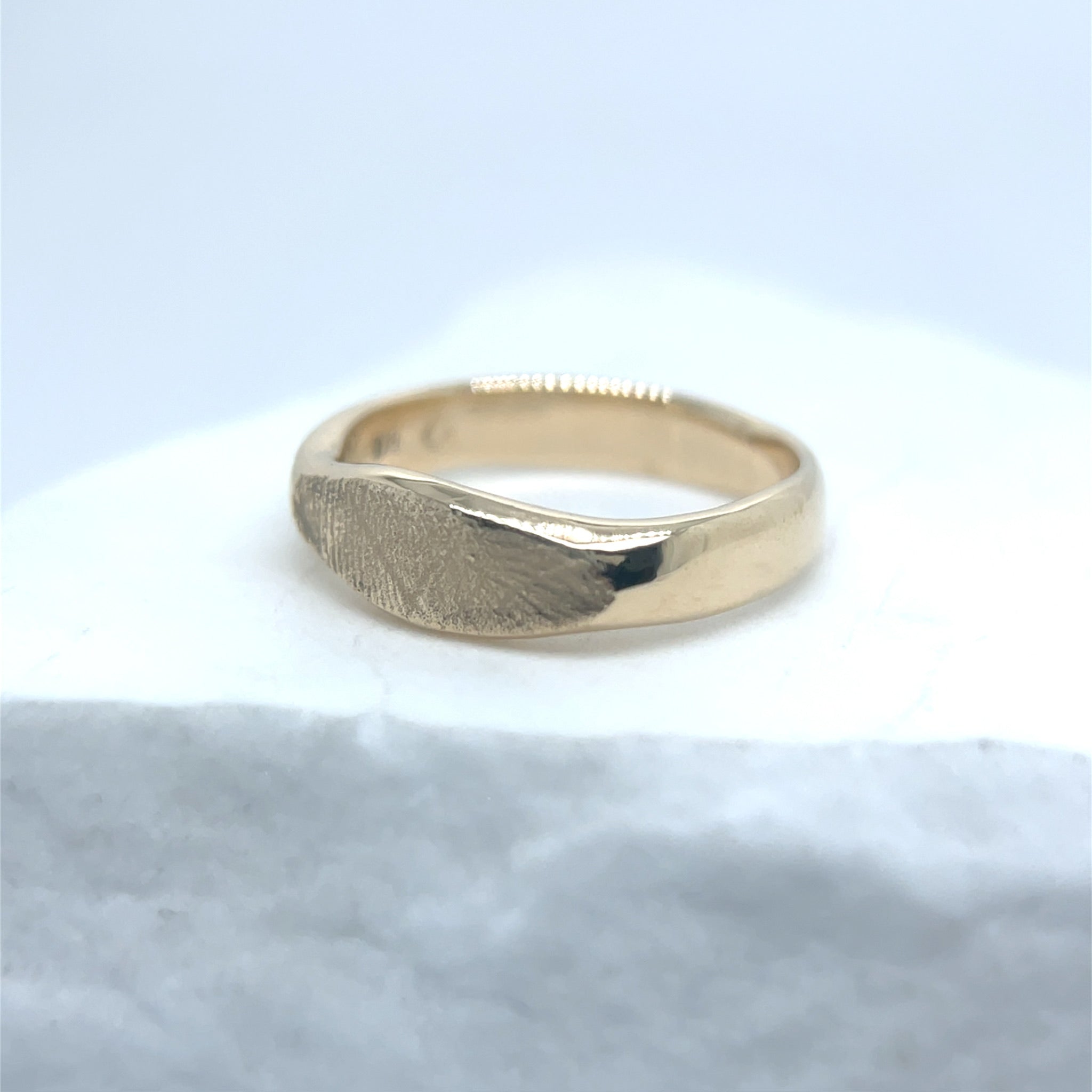 Gold ring on a light blue marble surface