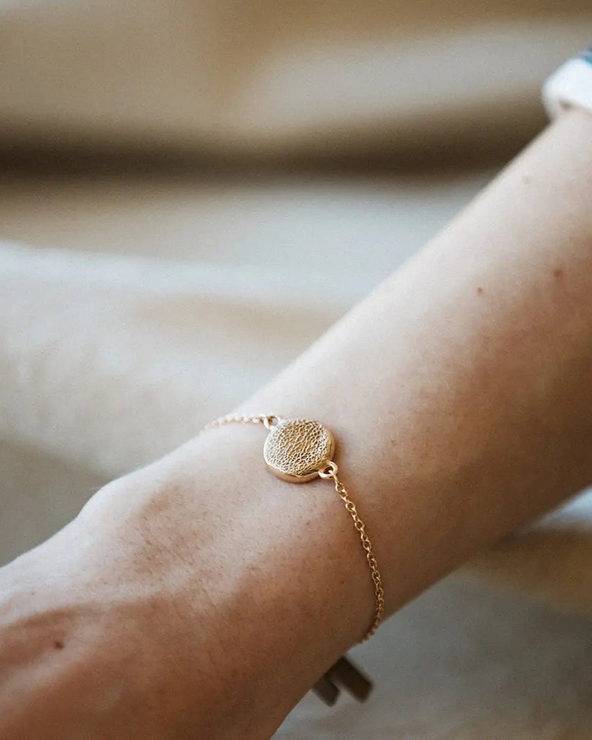 Gold bracelet on a wrist with a blurred background